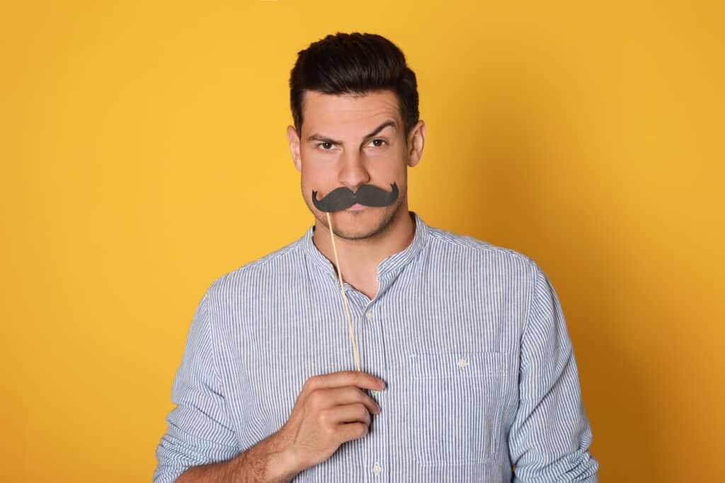 Funny man with fake mustache on yellow background movember